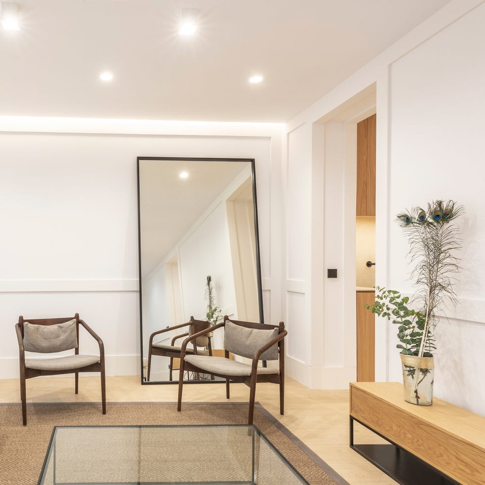 salón de diseño moderno con butacas de madera y espejo de suelo de gran formato