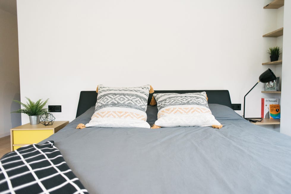 dormitorio moderno con cama negra y mesita de noche de madera y color amarillo