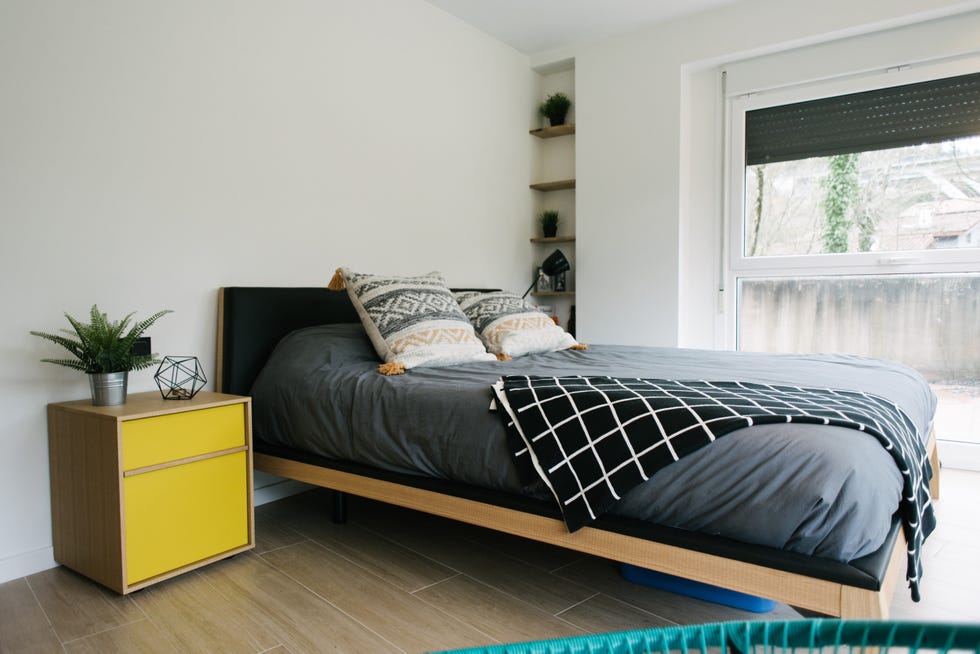 dormitorio moderno con cama negra y mesita de noche de madera y color amarillo