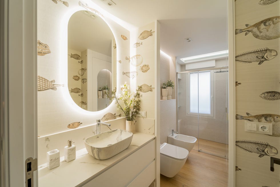 baño con mueble blanco volado y papel pintado con dibujos de peces