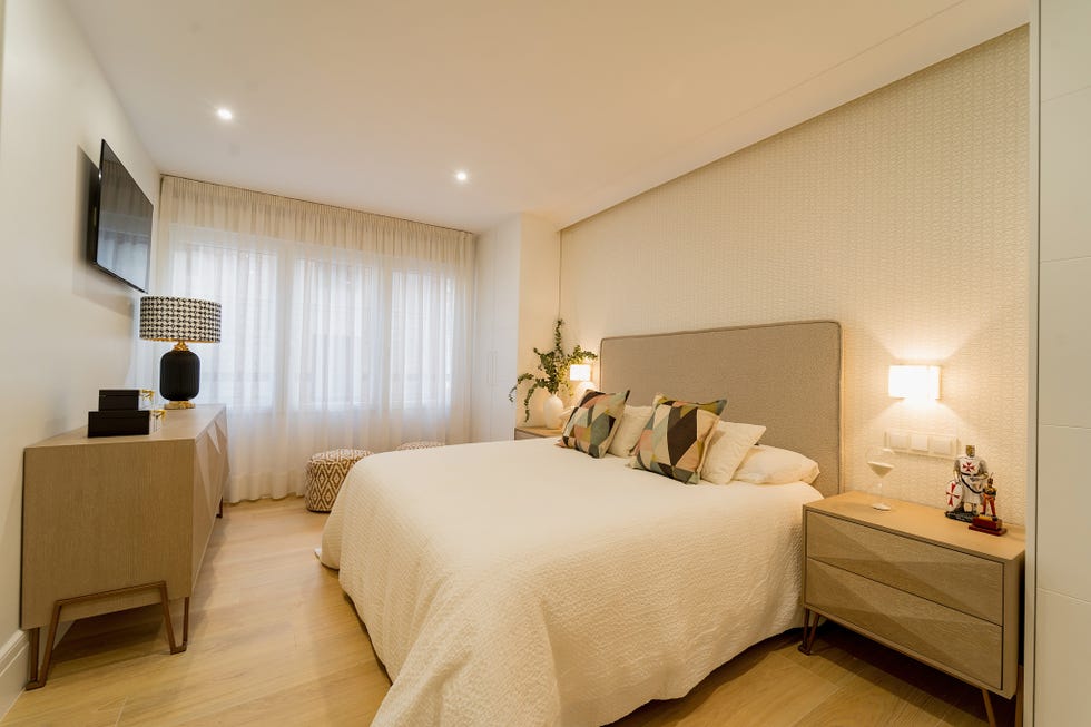 dormitorio con mesillas y cómoda de madera y cama con cabecero tapizado en beige