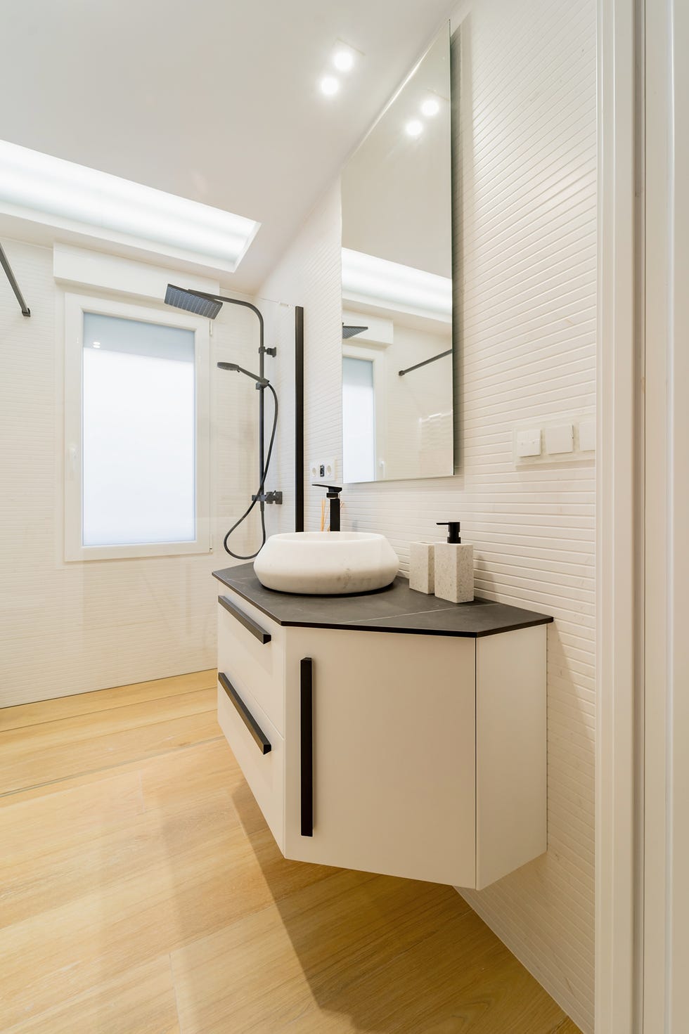 baño con mueble blanco volado y encimera de mármol negro