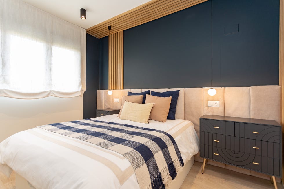 dormitorio con cabecero acolchado en color beige y mesitas de noche de estilo art déco