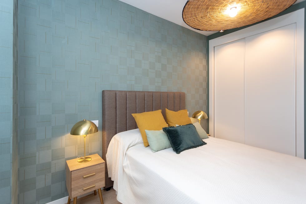 habitación con papel pintado con estampado a cuadros y cabecero tapizado en tela gris acolchada