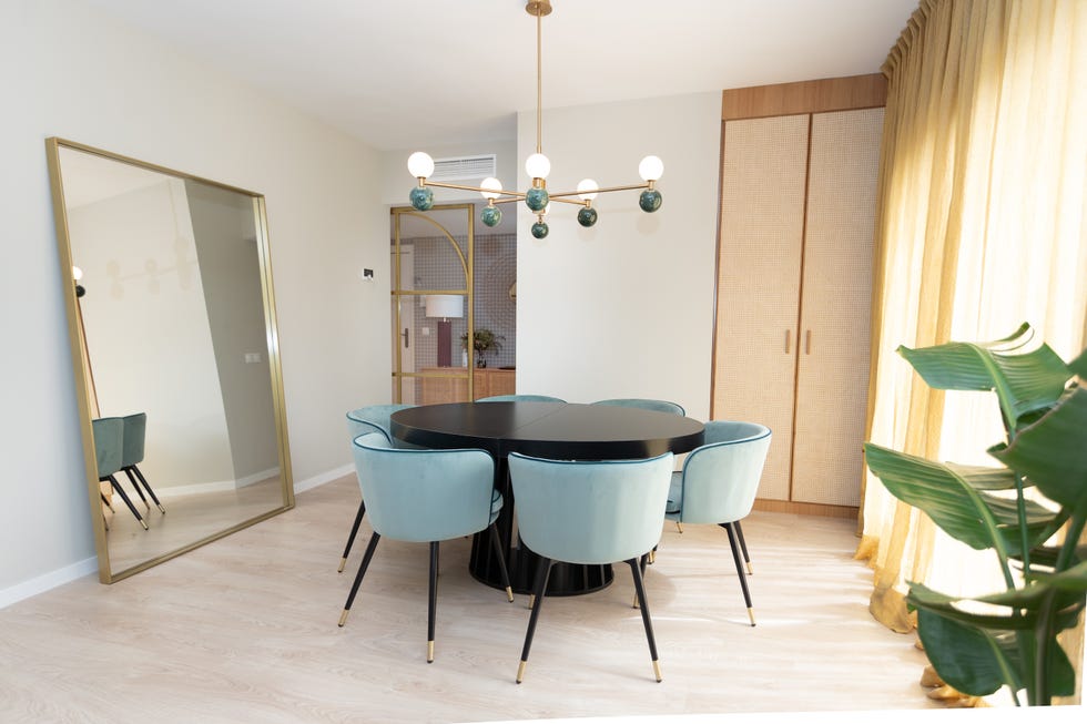 comedor de estilo art déco con mesa redonda negra, sillas de terciopelo azul y lámpara mid century