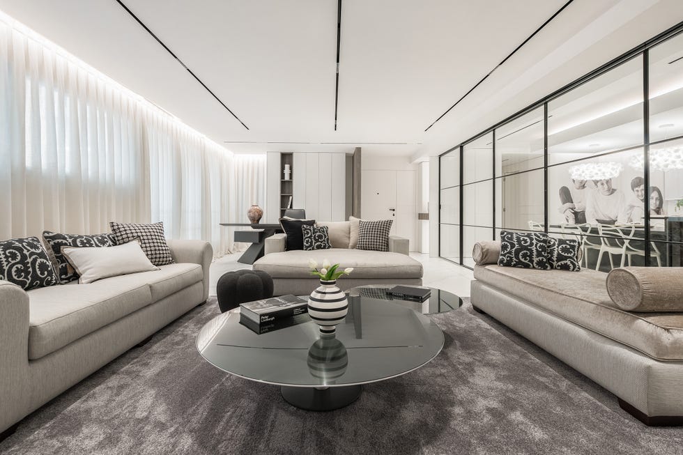 salón con sofás grises y cocina con cristalera