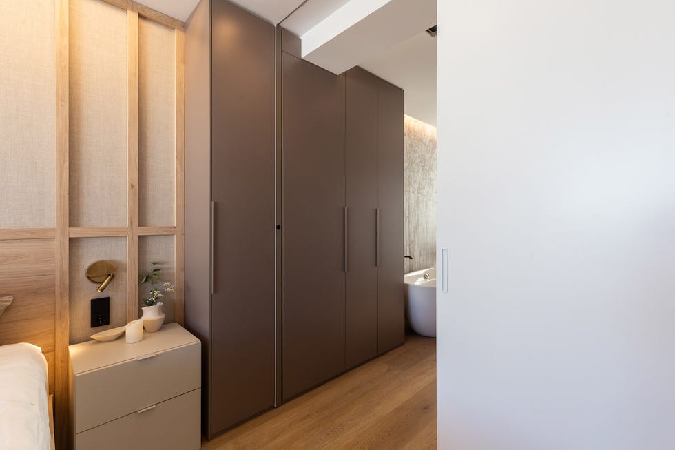 dormitorio con baño en suite y armario con puertas marrones