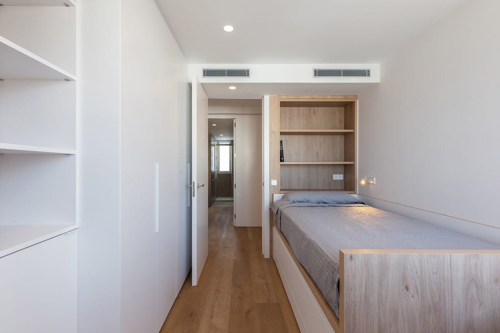 habitación con cama nido y estantería de madera integrada