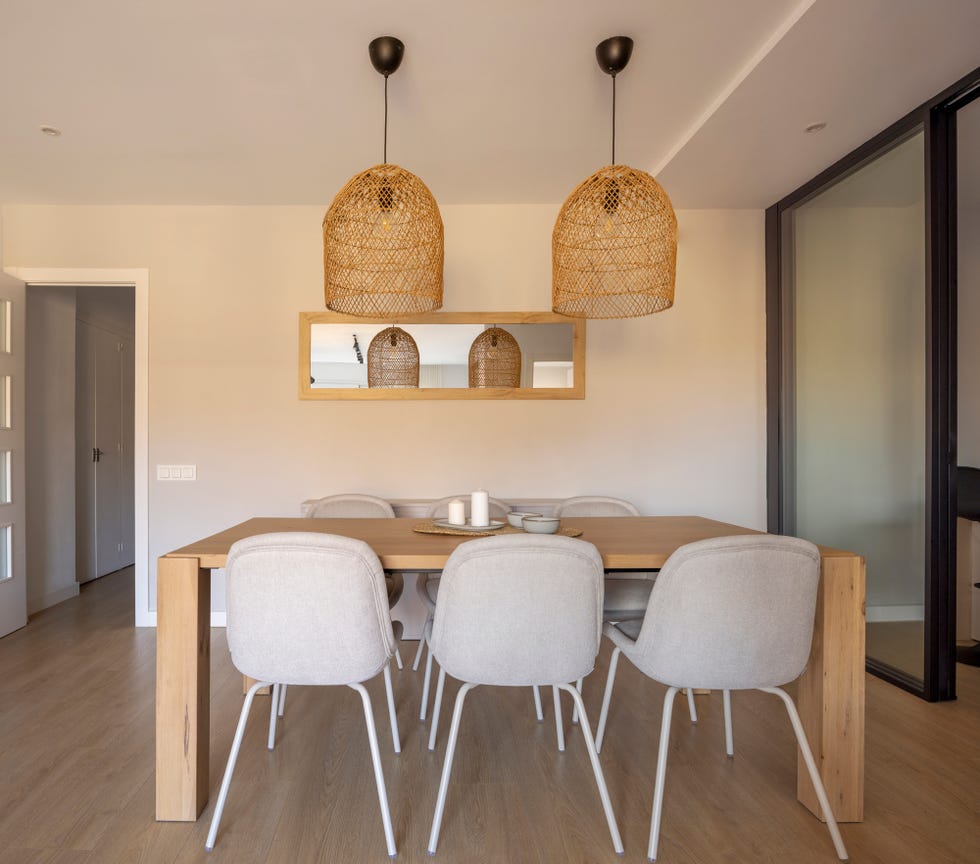 mesa de comedor de madera, sillas tapizadas en beige y lámparas de fibras