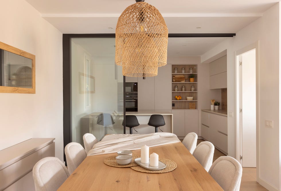 mesa de comedor de madera y al fondo cocina con puerta corredera