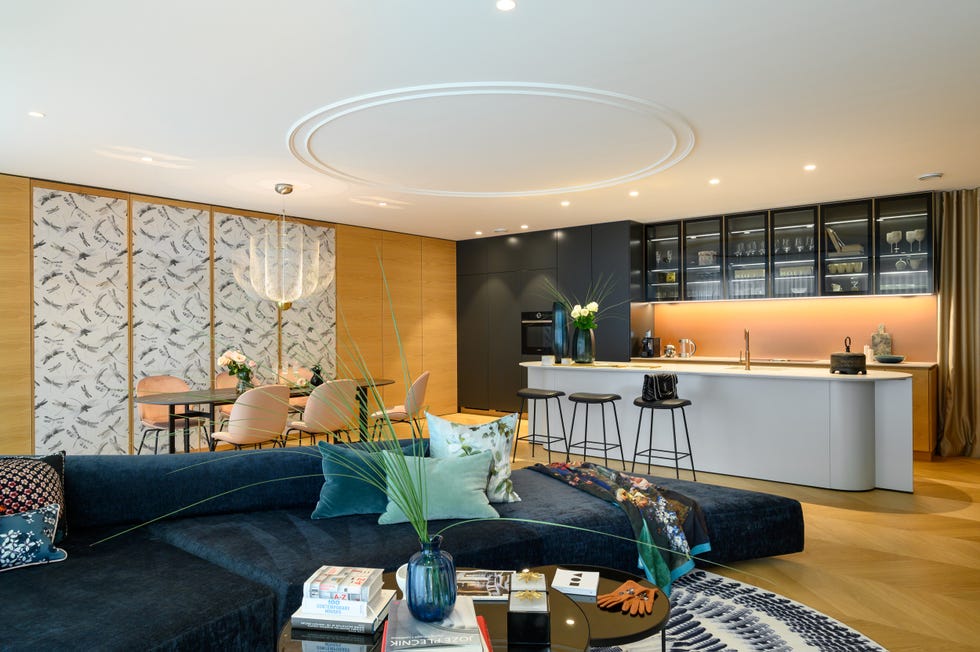 salón con sofá de terciopelo azul con comedor y cocina de diseño moderno integrados