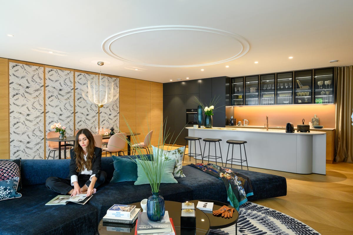 salón con sofá de terciopelo azul con comedor y cocina de diseño moderno integrados
