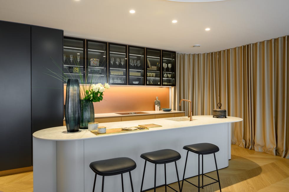 cocina abierta moderna con isla central con encimera de mármol y taburetes negros