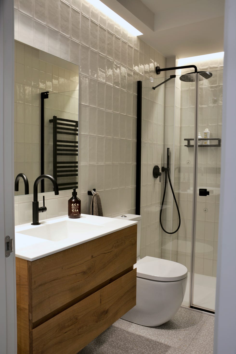 baño con ducha a ras de suelo, azulejos blancos y mueble bajo lavabo de madera