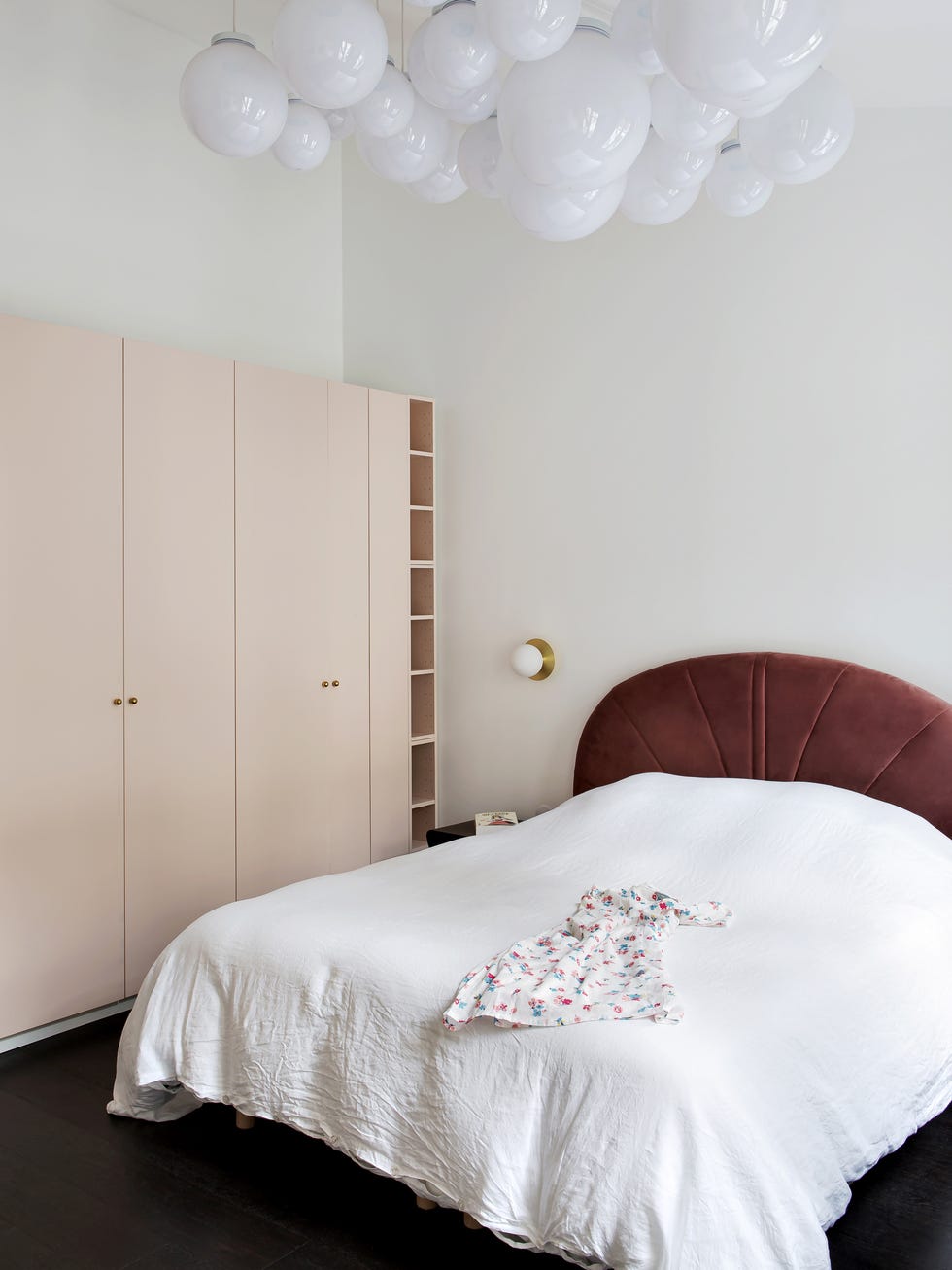 dormitorio con cama con cabecero de terciopelo granate y armario de color rosa pastel