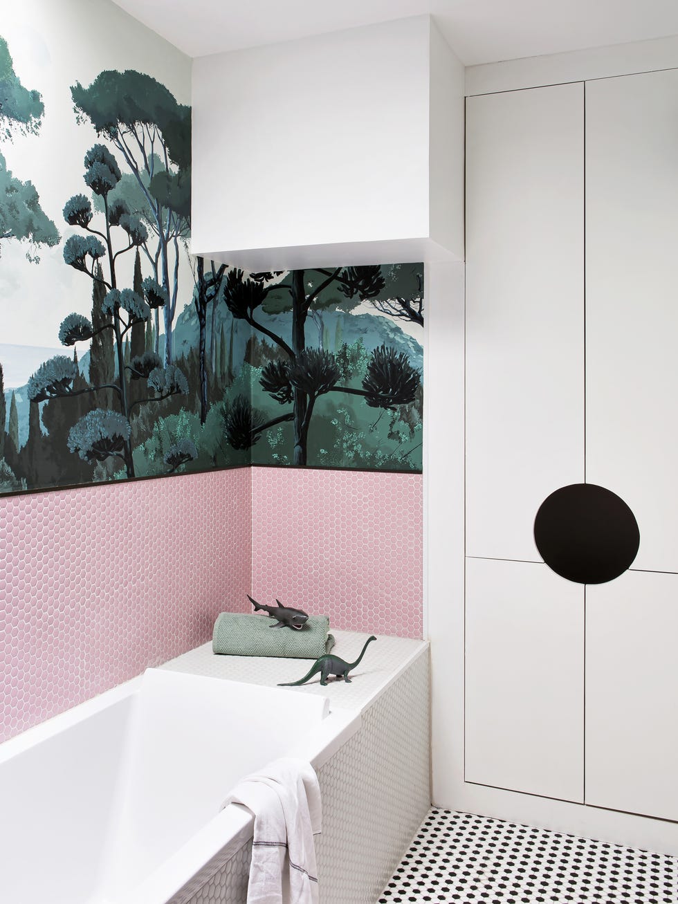 baño con papel pintado con dibujos de un bosque y azulejos tipo panal de abeja en color rosa