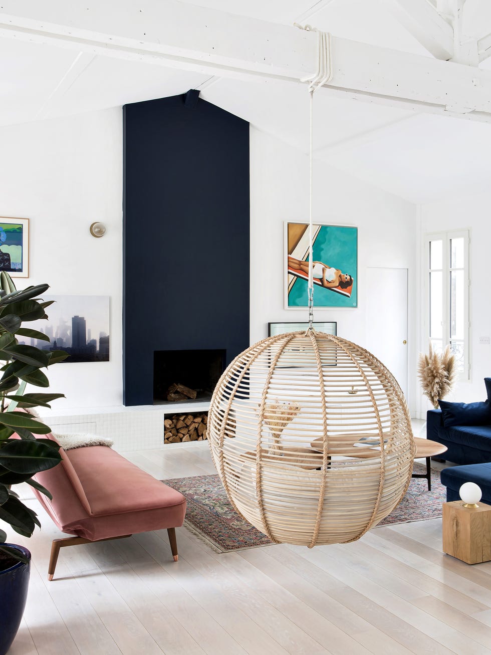salón de diseño moderno con chimenea, sofá de terciopelo azul y columpio de ratán