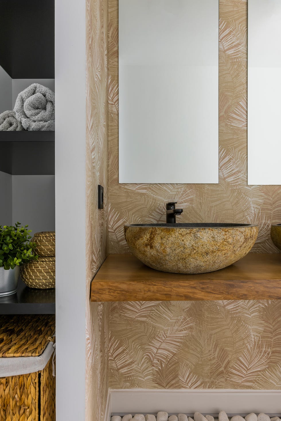 baño con papel pintado botánico, encimera de madera y lavabos de piedra