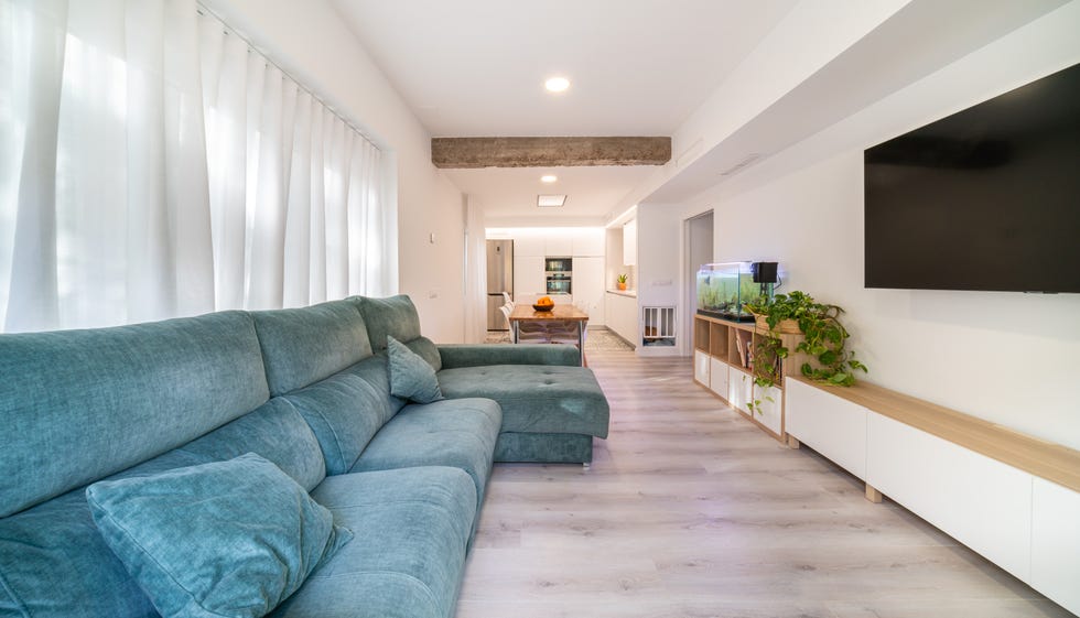 salón moderno y abierto a la cocina con sofá con chaiselongue de terciopelo azul