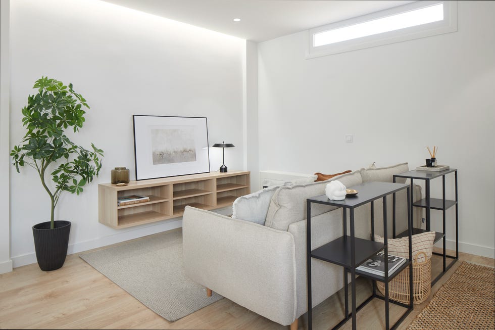 salón abierto de diseño nórdico con sofá gris y consolas negras