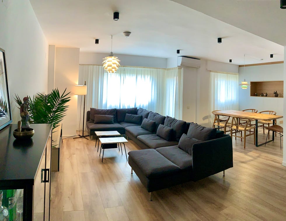 salón comedor con sofá negro y mesa de madera
