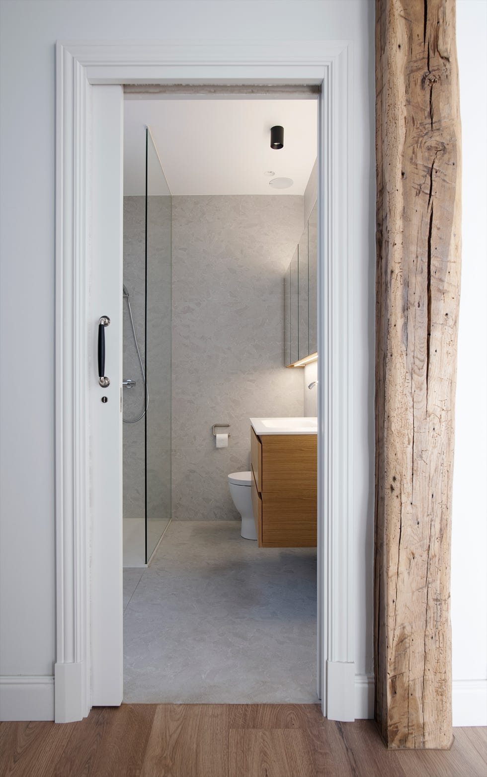 baño con ducha a ras de suelo revestido con microcemento y mueble de lavabo de madera suspendido