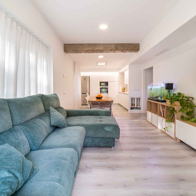 salón moderno y abierto a la cocina con sofá con chaiselongue de terciopelo azul