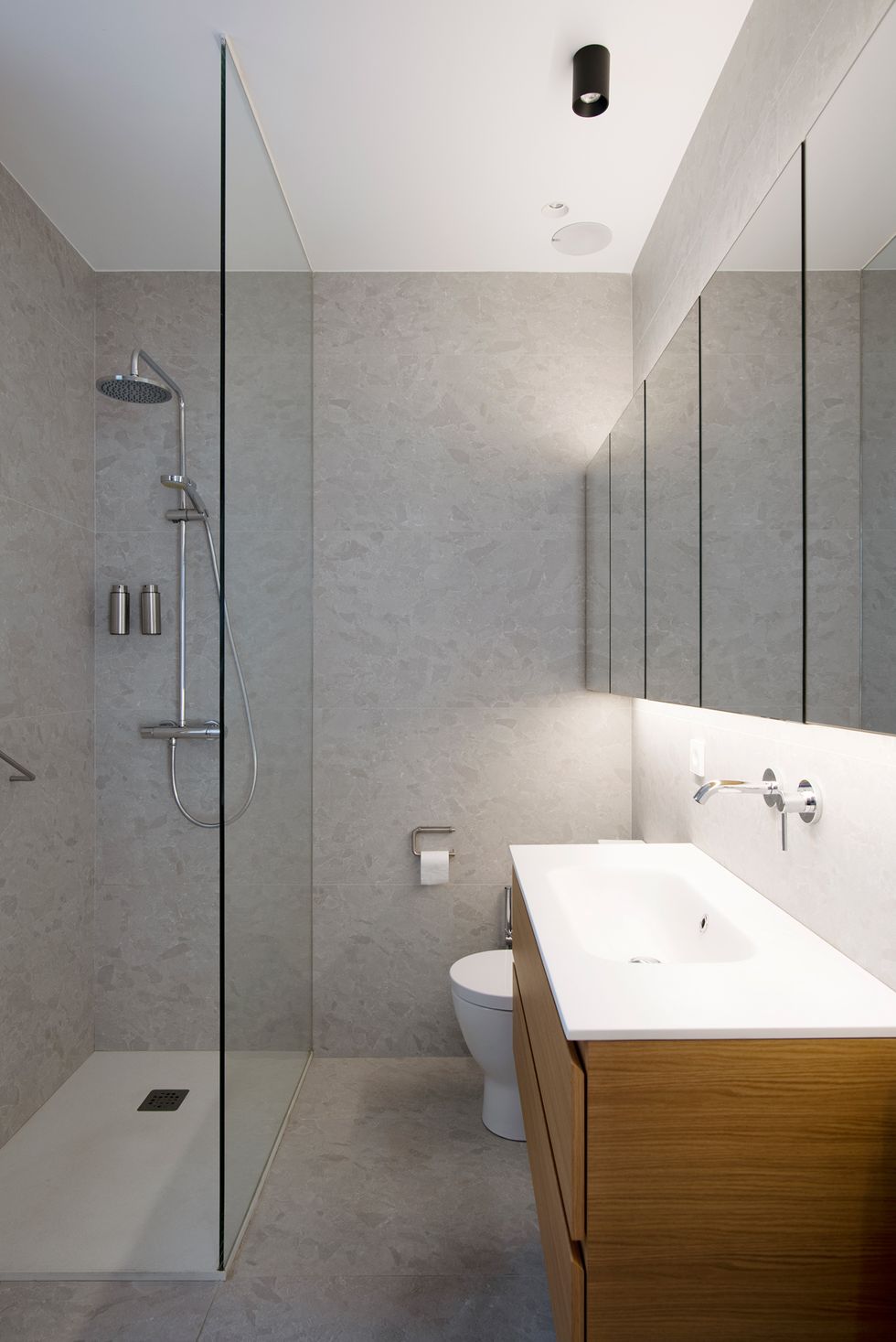 baño con ducha a ras de suelo revestido con microcemento y mueble de lavabo de madera suspendido