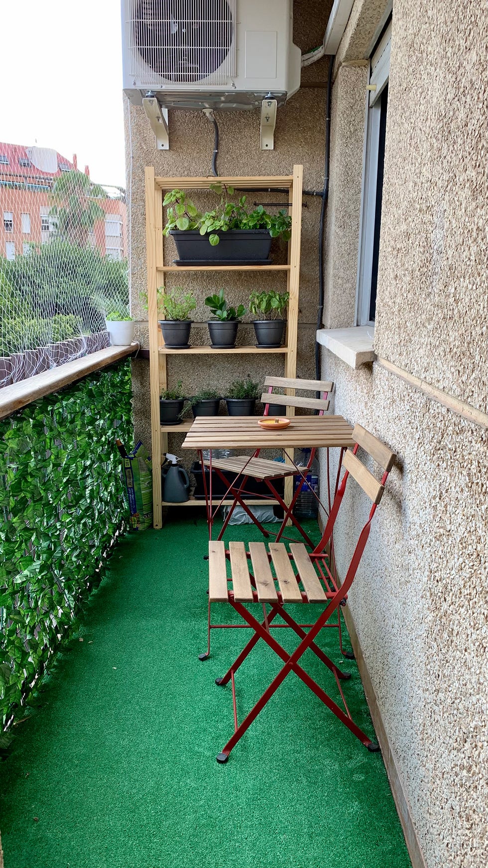 terraza con césped artificial y mesa y sillas plegables