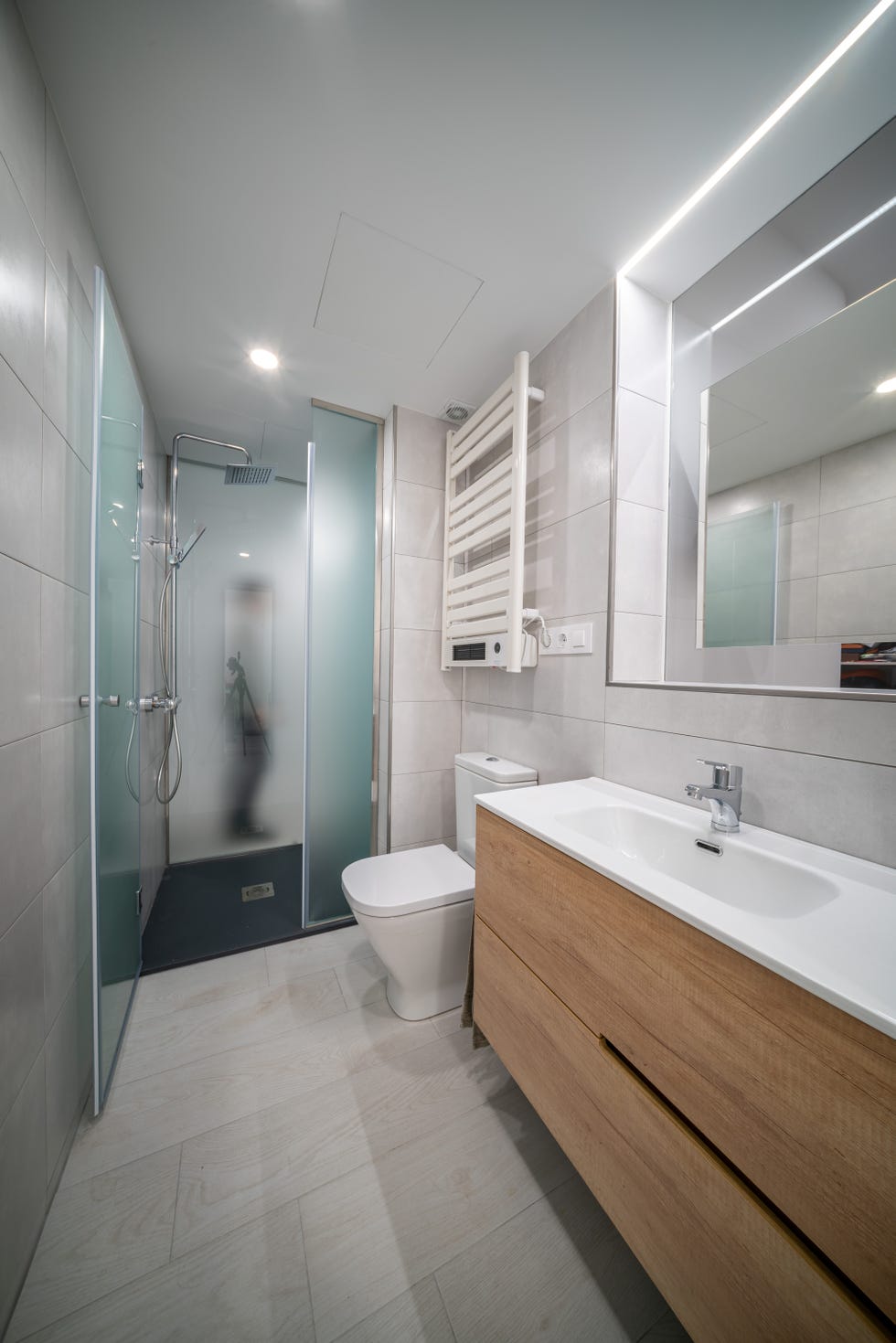 baño con ducha y mueble volado de madera