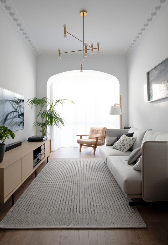 salón moderno con sofá gris, butaca de madera, mueble tv de madera y lámpara dorada mid century