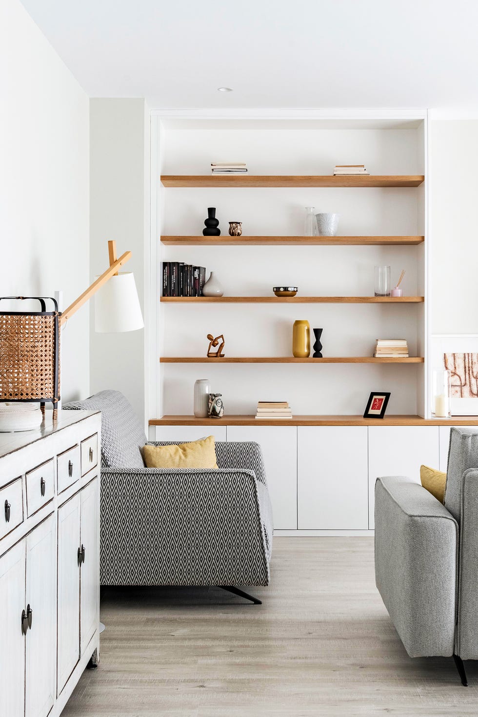 salón con baldas de madera y mueble tv blanco