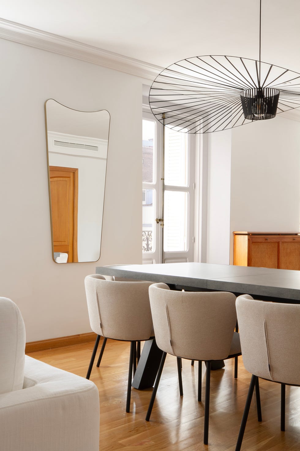 mesa de comedor con sillas tapizadas en beige y lámpara metálica negra