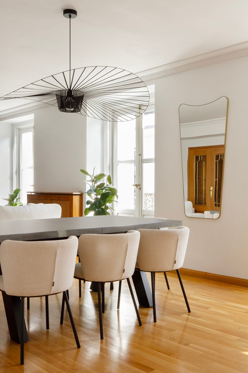 mesa de comedor con sillas tapizadas en beige y lámpara metálica negra