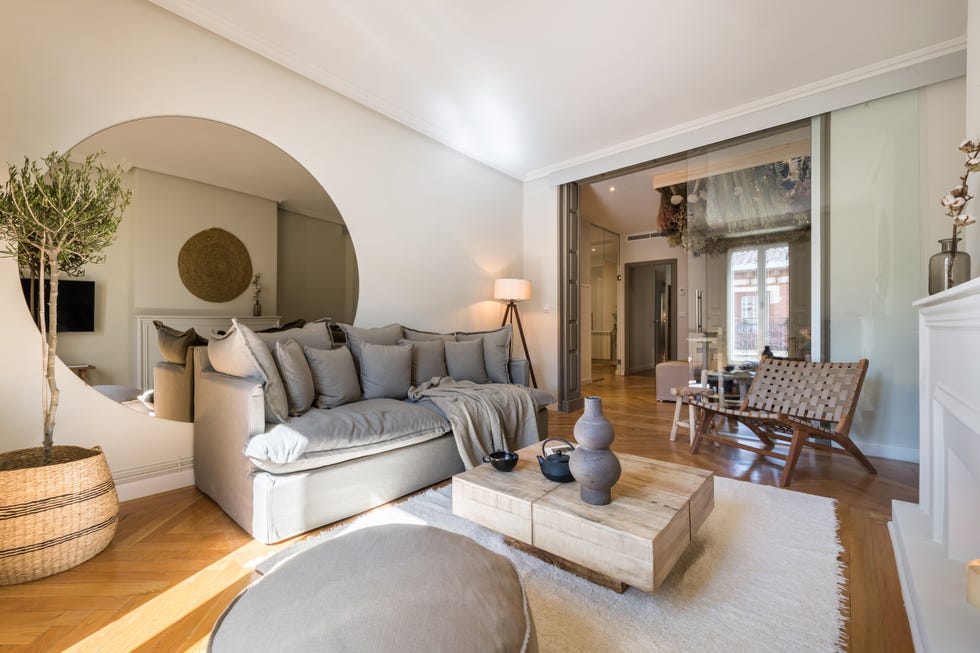 salón de estilo boho chic con chimenea blanca, sofá de lino gris y mesa de centro de madera