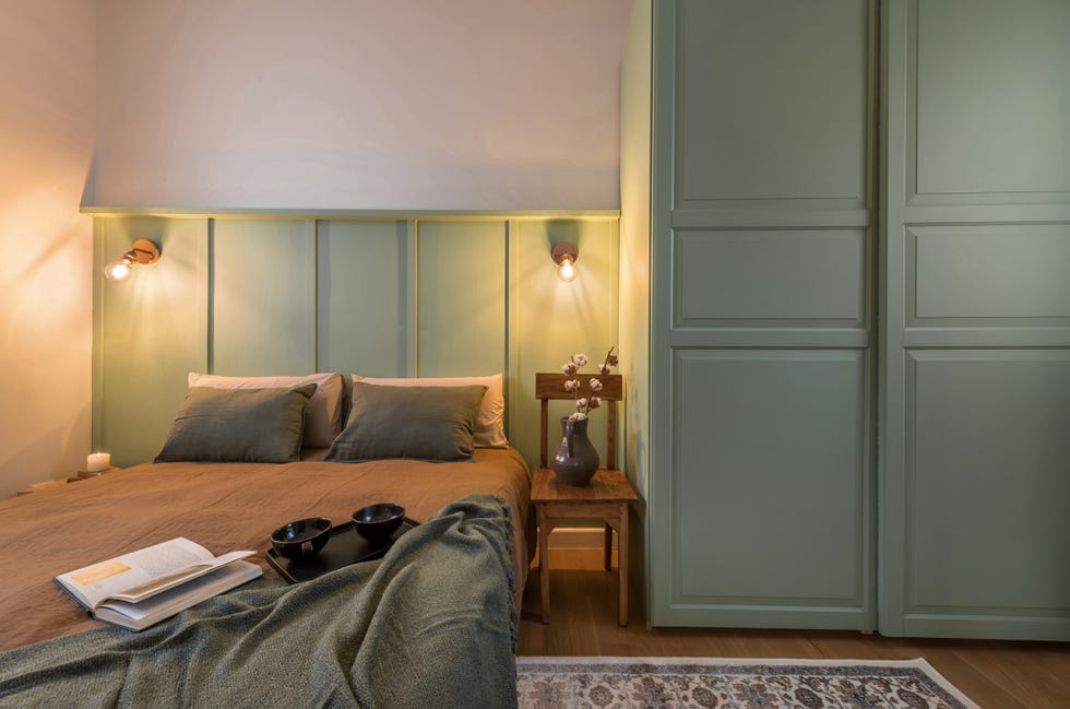 dormitorio con arrimadero con molduras decorativas en color verde como cabecero y armario a juego