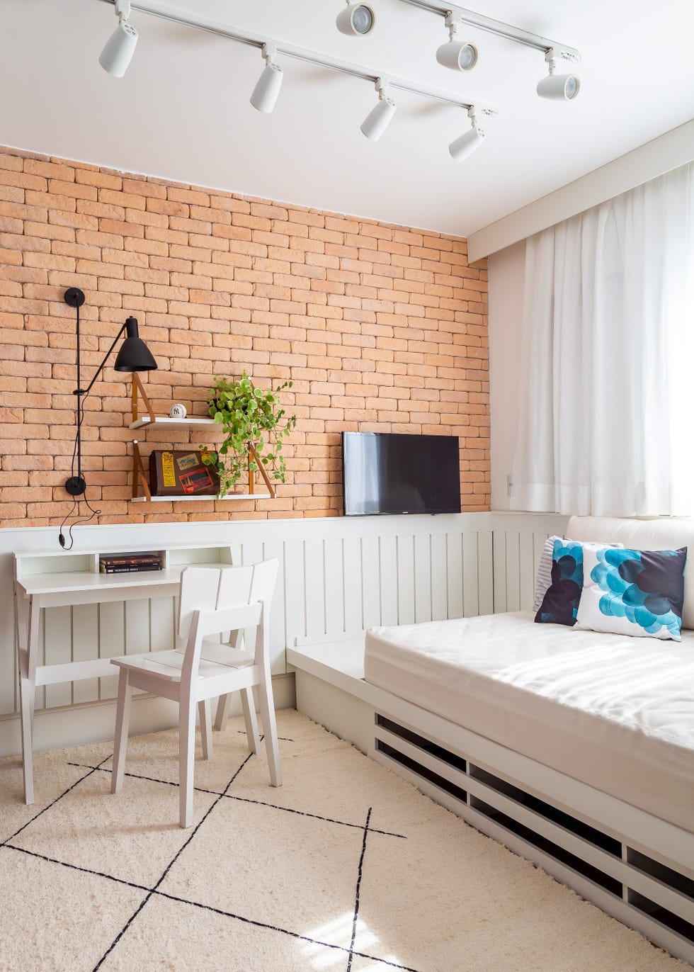 habitación con escritorio y cama y pared de ladrillo visto