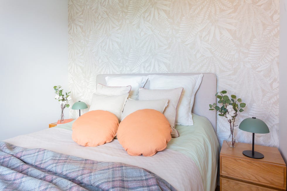 dormitorio con papel pintado con motivos botánicos beige y cabecero a juego