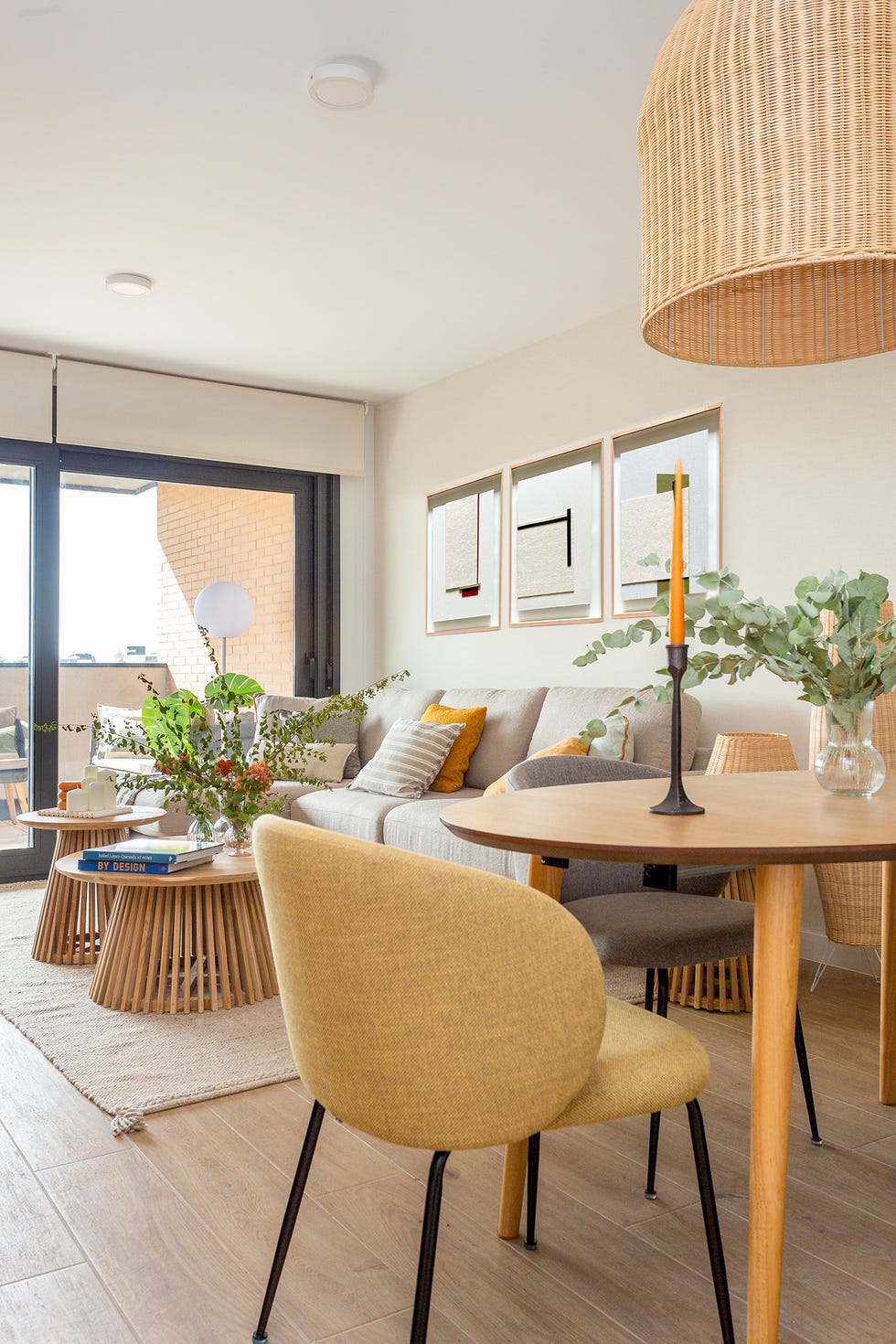 salón comedor con sofá con chaiselongue gris y mesas de centro de madera redondas