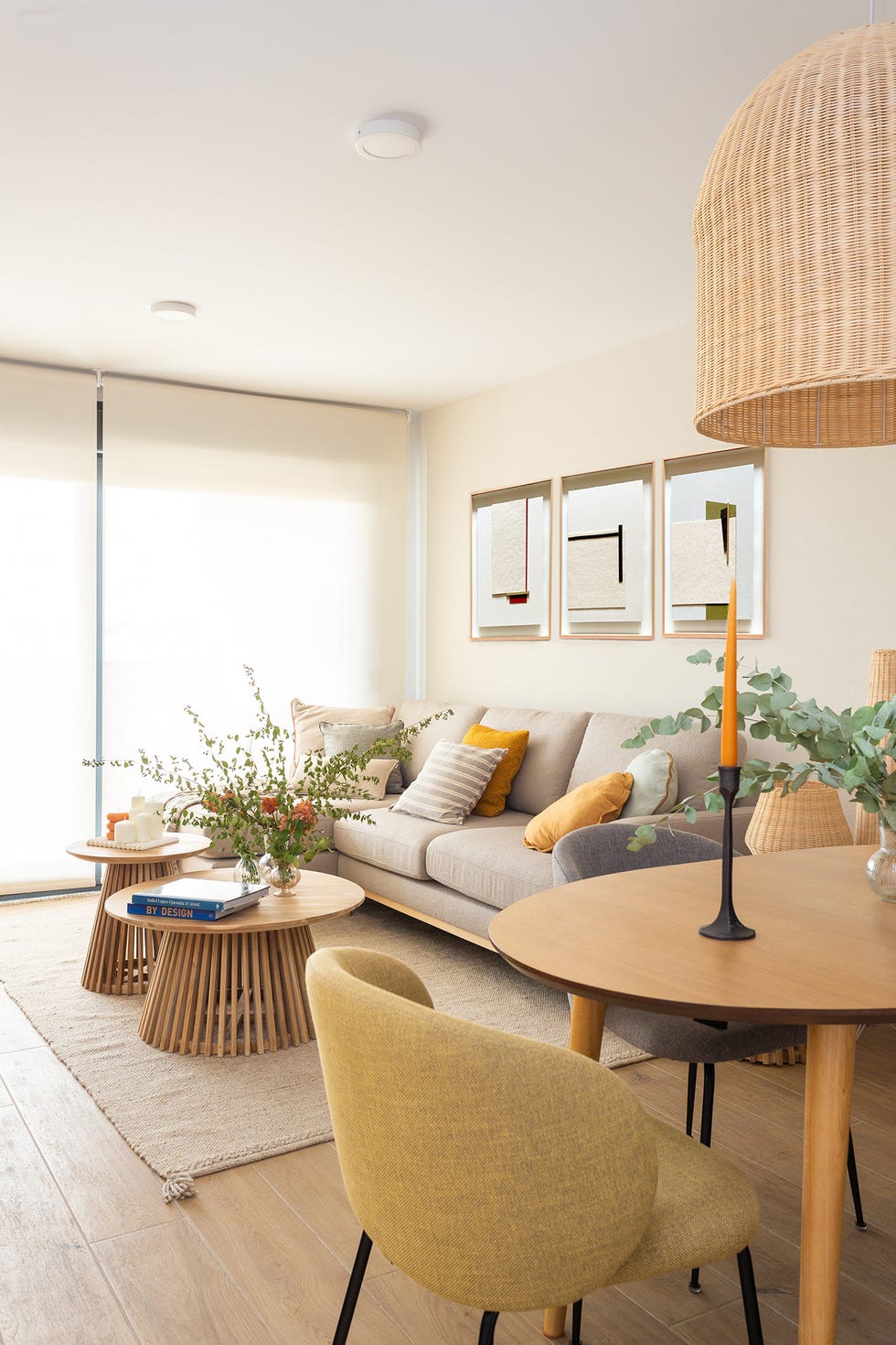 salón comedor con sofá con chaiselongue gris y mesas de centro de madera redondas