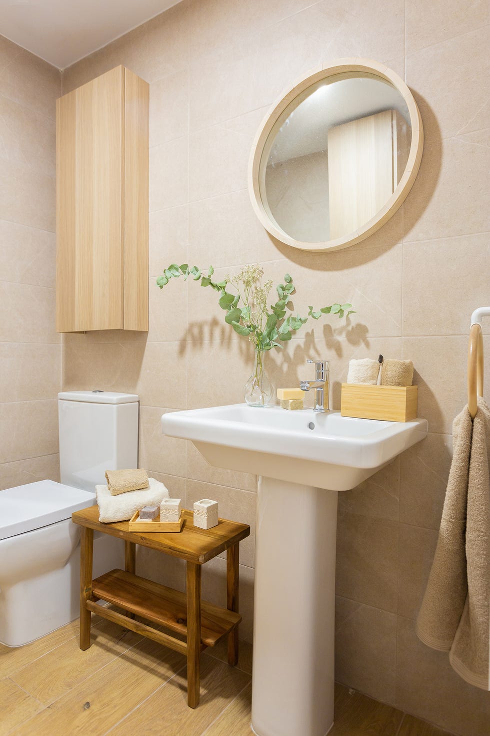 baño con espejo redondo y estantería y banqueta de madera