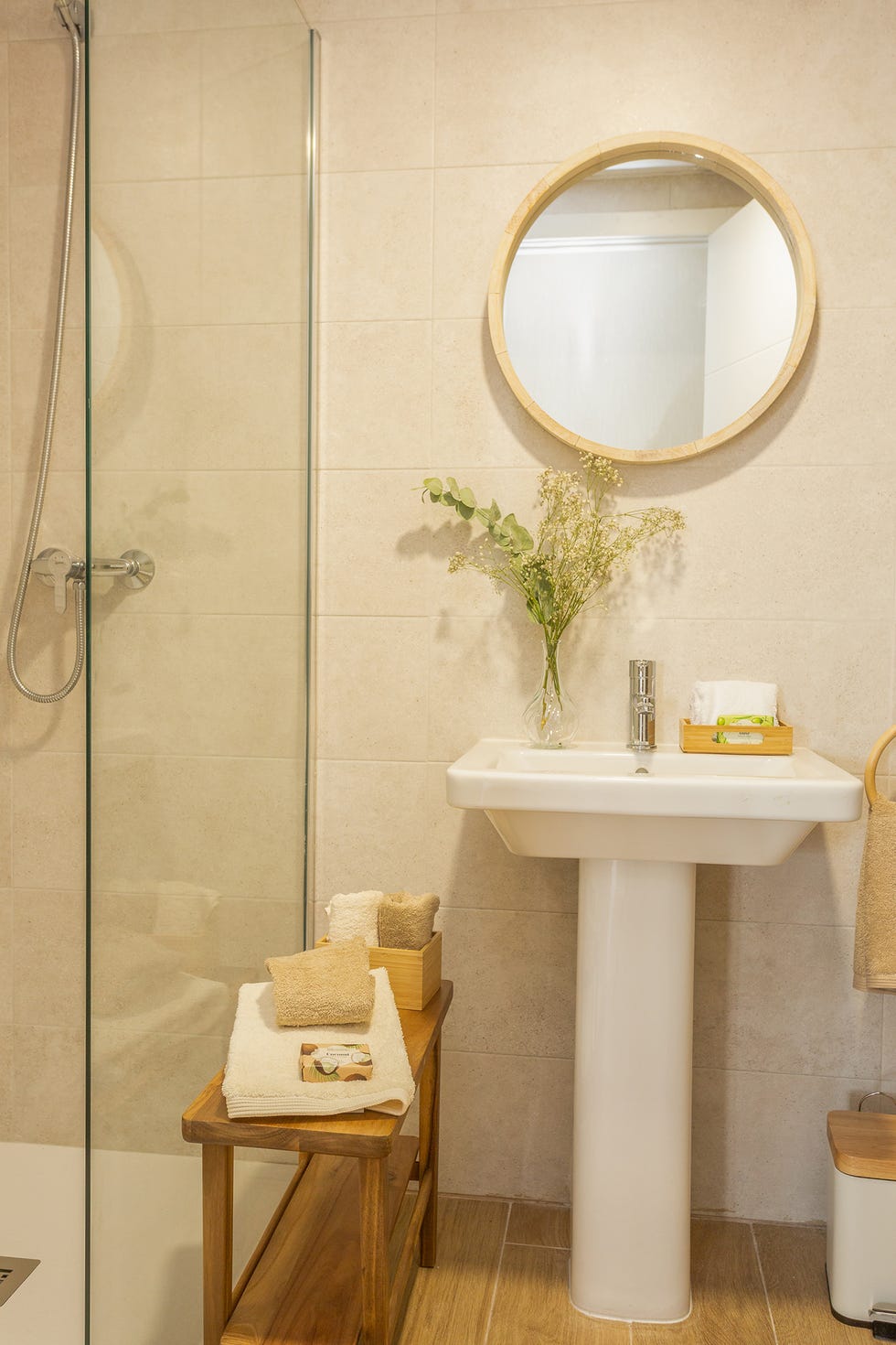baño con ducha, espejo redondo y banqueta de madera