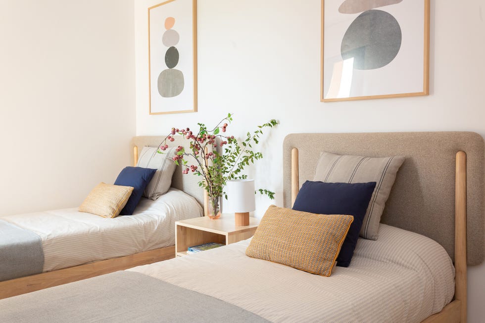 habitación con dos camas de madera con cabeceros tapizados en beige