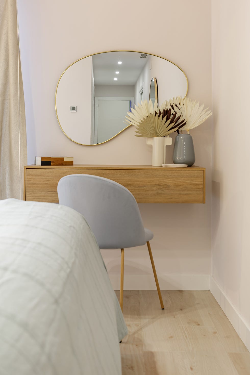 tocador de madera volado, silla de terciopelo azul y espejo con forma orgánica