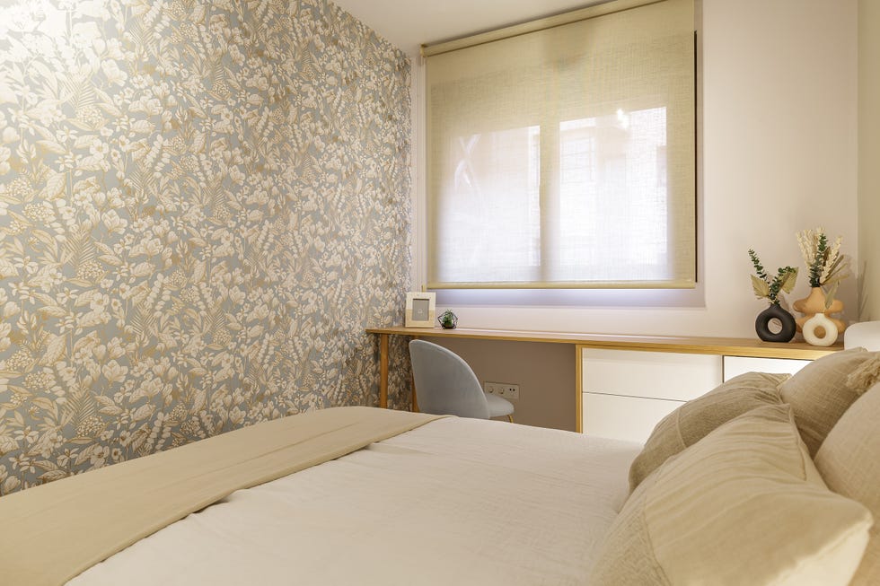 dormitorio con papel pintado floral y escritorio en blanco y madera