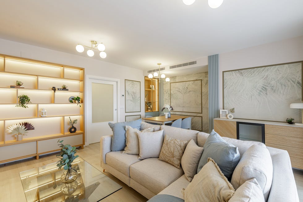 salón comedor con estantería de madera con retroiluminación, sofá rinconera gris y molduras decorativas