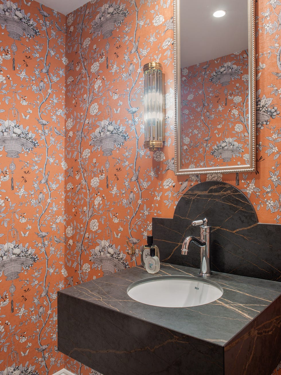 aseo con papel pintado naranja con motivos de flores y lavabo volado