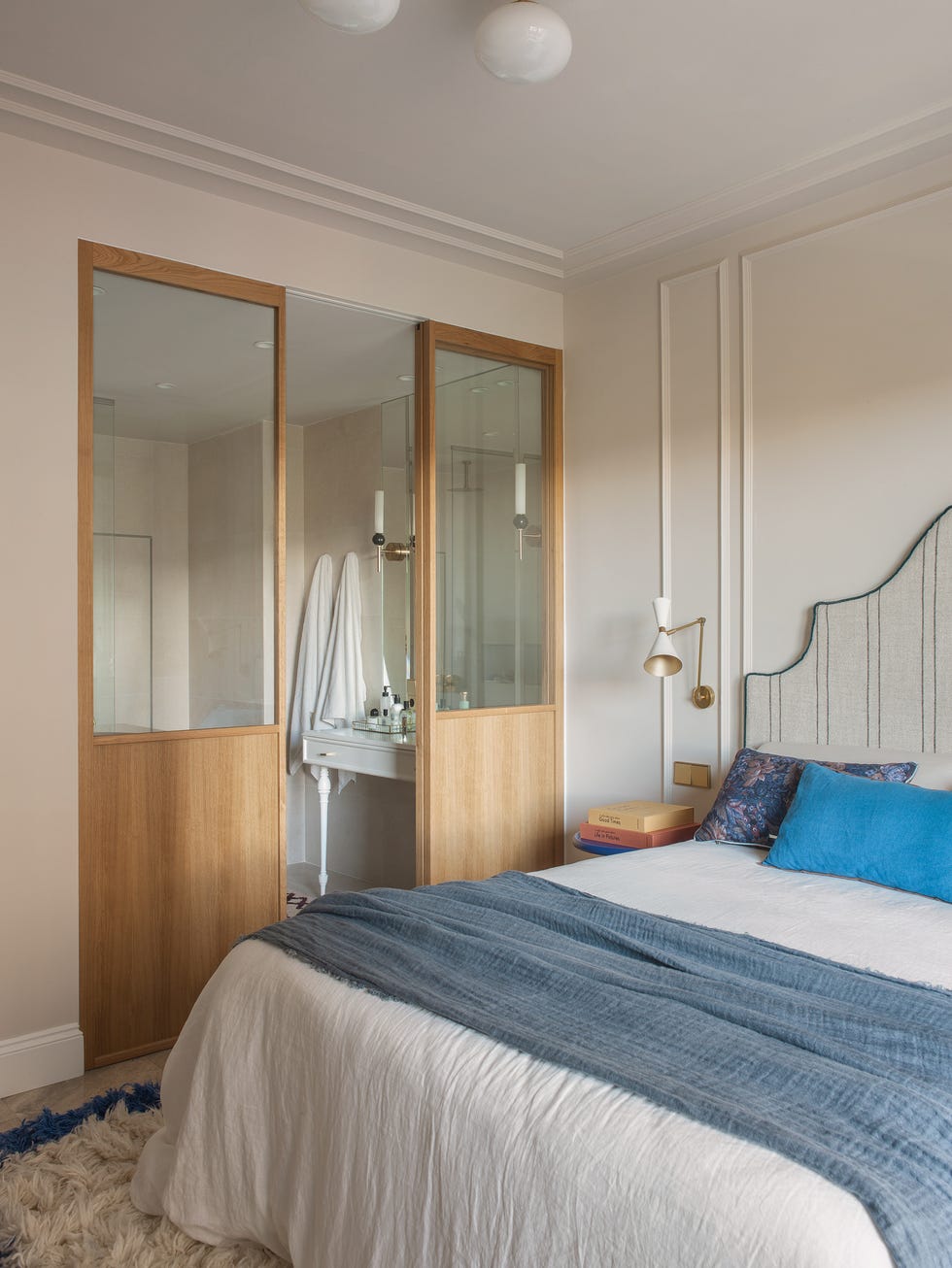 dormitorio con baño en suite a través de unas puertas correderas de madera y cristal