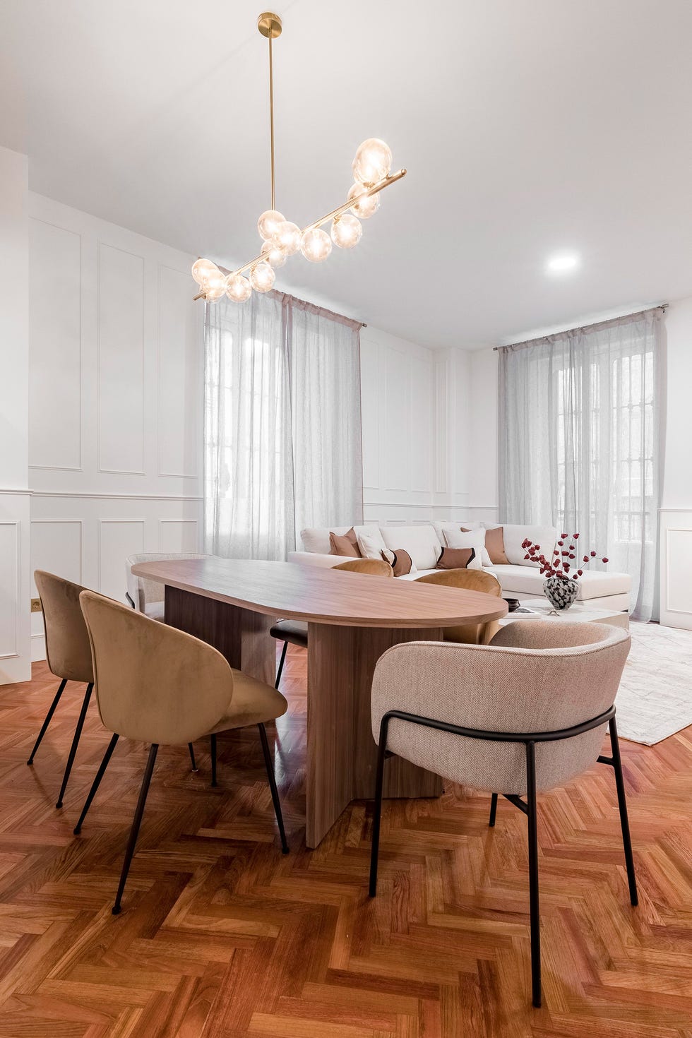 mesa de comedor de madera ovalada, sillas y lámpara suspendida con bolas de cristal