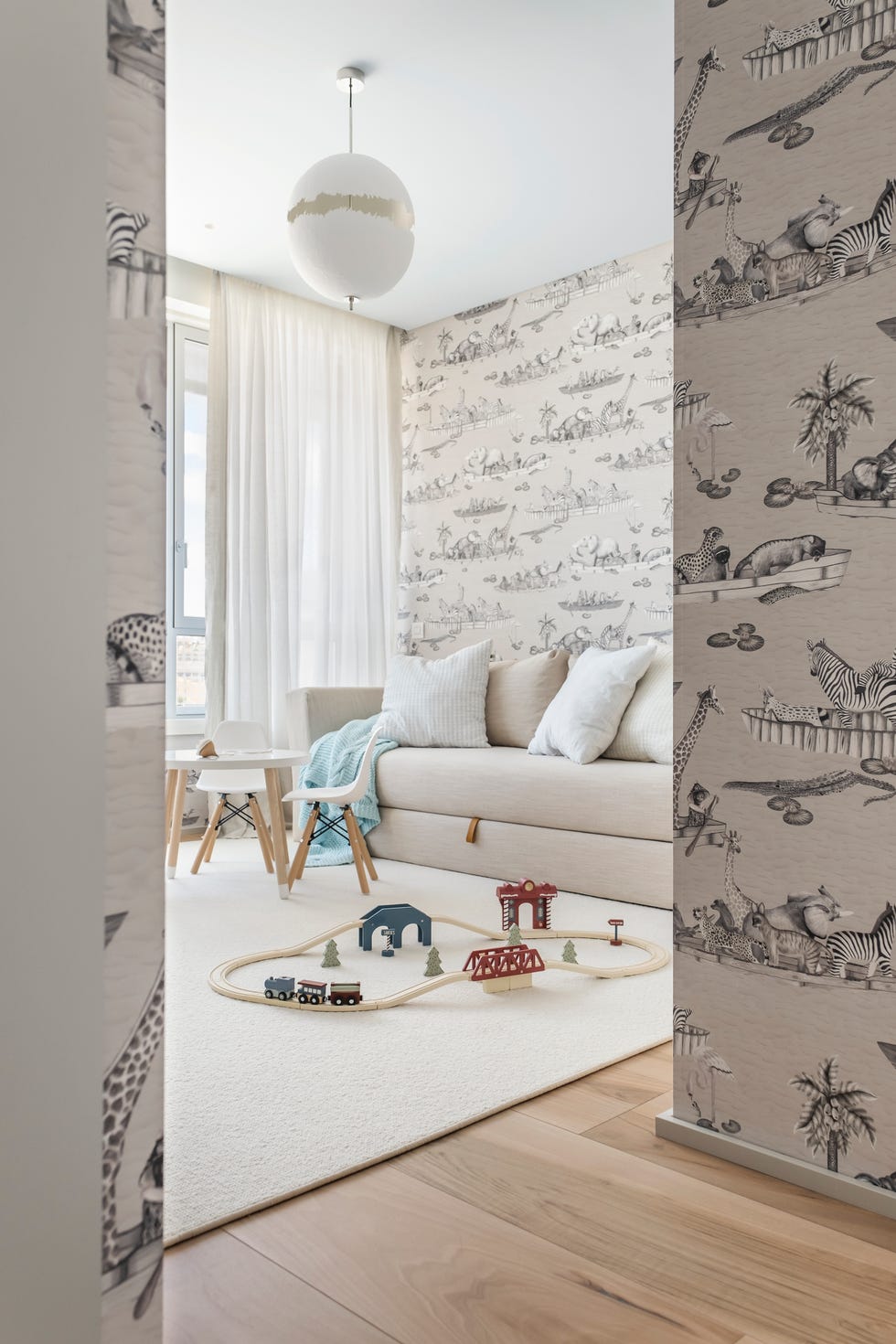zona de juegos infantil con papel pintado de animales y sofá cama beige